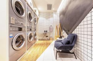 郑州郑州航空港新郑国际机场亚朵酒店的洗衣房配有洗衣机和蓝色椅子 更多14张照片