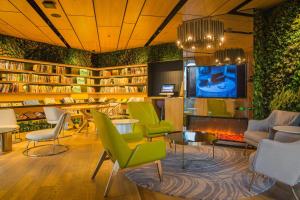 a library with green chairs and a tv and a fireplace at Atour Hotel Canal Hangzhou in Hangzhou