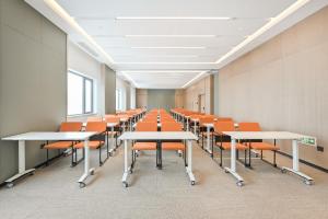 an empty classroom with desks and orange chairs at Atour Hotel Beijing Hepingli UIBE in Beijing
