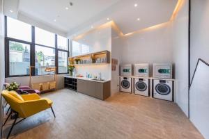 a laundry room with three washing machines and a yellow chair at Atour Hotel Hefei Shushan High-Tech Industrial Park West Changjiang Road in Hefei