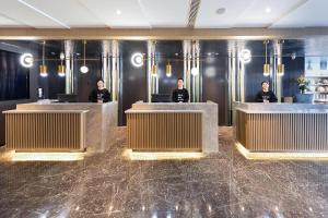 a group of people sitting at reception desks in a lobby at Atour Hotel Lianyungang City Government in Lianyungang