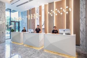 a group of people sitting at a counter with laptops at Atour Hotel Meishan Government Affairs Center in Meishan