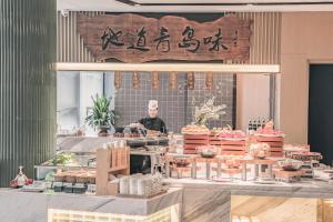 a man standing behind a counter in a kitchen with food at Atour Hotel Qingdao CBD Hangzhou Road in Qingdao