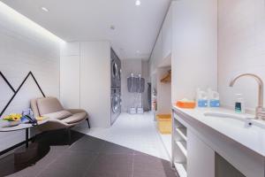 Baño blanco con lavabo y silla en Atour Hotel Nanjing Xianlin Unviersity Town, en Nanjing