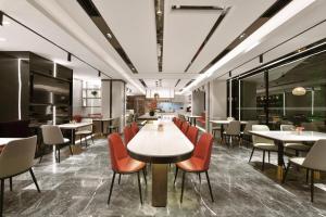 a restaurant with white tables and orange chairs at Atour Light Hotel Shenyang High-Speed Railway Station in Shenyang