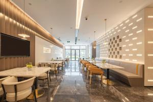 a restaurant with tables and chairs and a flat screen tv at Atour Hotel Shanghai New International Expo Center South Yanggao Road in Shanghai