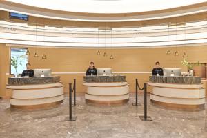 three people sitting at a counter in a lobby at Atour Hotel Ezhou City Government in Ezhou