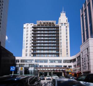Atour Hotel Hohhot Drum Tower Manduhai في هوهوت: مبنى ابيض كبير فيه سيارات تقف امامه