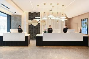 three people standing in a lobby with their laptops at Atour Hotel Beijing Hepingli UIBE in Beijing