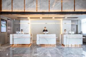 trois personnes assises sur un bureau avec leur ordinateur portable dans l'établissement Atour Hotel Huzhou Nanxun Ancient Town, à Huzhou