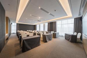 a conference room with white chairs and tables and windows at Atour Hotel Ningbo Xiangshan Binhai Avenue in Xiangshan