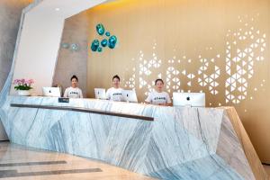 Czterech mężczyzn siedzących przy ladzie z laptopami w obiekcie Atour Hotel Kunming City Government Xishan Dianchi Lake w mieście Kunming