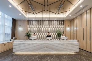 three people sitting at a large table with their laptops at Atour Hotel Yancheng ETDZ in Yancheng