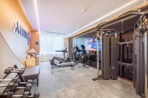 Atour Hotel Wuhan International Expo Center في ووهان: صالة ألعاب رياضية مع أجهزةالجري والتمرين في الغرفة