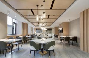 a dining room with white tables and chairs at Atour Hotel Jinan High-Speed East Railway Station in Jinan