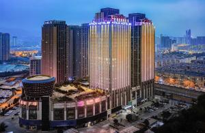 Atour Hotel Kunming City Government Xishan Dianchi Lake في كونمينغ: اطلالة على مبنى كبير في مدينة بالليل