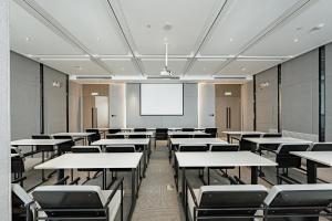 an empty classroom with tables and chairs and a projection screen at Atour Hotel Urumqi Zhongyinggong South Beijing Road in Ürümqi