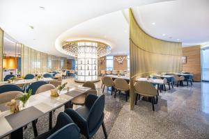 Un restaurante con mesas y sillas y una lámpara de araña. en Atour S Hotel Wuhan Chuhehanjie, en Wuhan