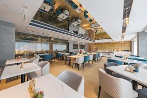 un restaurante con mesas blancas y sillas azules en Atour Hotel Chongqing West Station en Chongqing