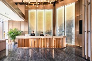 two people sitting at a reception desk in a lobby at Atour Hotel Sanhe Yanjiao Development District in Sanhe