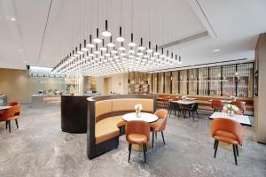 a restaurant with tables and chairs and a chandelier at Atour Hotel Qingdao Jiaodong International Airport in Jiaozhou