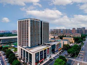 a tall building in a city with a lot of buildings at Atour Hotel Jiaxing Pinghu in Pinghu