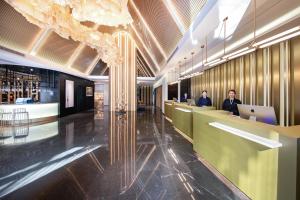 un vestíbulo con 2 personas sentado en un escritorio con un ordenador portátil en Atour S Hotel Wuhan Chuhehanjie, en Wuhan