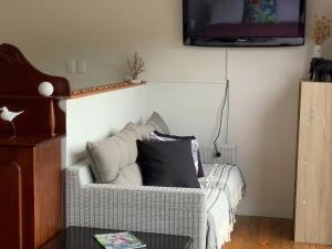 a living room with a couch and a tv at PACIFIC PARADISE COTTAGE in Tutukaka