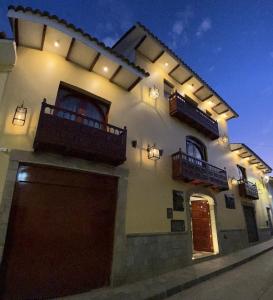 un gran edificio blanco con 2 balcones y un garaje en Hotel Hacienda Cusco Centro Historico, en Cusco