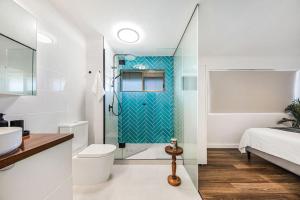 a bathroom with a shower and a toilet and a sink at Lovely 2bd Unit, Patio and views. Best weekly rate in Alexandra Headland