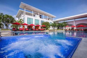 a swimming pool with red umbrellas in front of a hotel at D Varee Jomtien Beach, Pattaya in Jomtien Beach