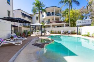 a swimming pool with chairs and umbrellas next to a building at Riviera Noosa Resort in Noosaville
