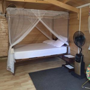 Cette chambre en bois comprend un lit à baldaquin. dans l'établissement Ambalabaa, à Saint-Philippe