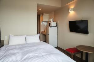 Habitación de hotel con cama y TV en New Normal Condo in NAHA AIRPORT ニューノーマルコンドイン那覇エアポート en Naha