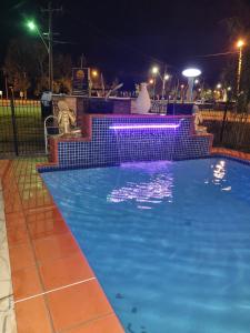 una piscina notturna con illuminazione viola di Country Plaza Motel Taree a Taree