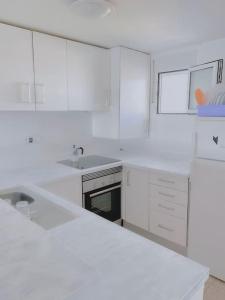 a white kitchen with white cabinets and a sink at Amazing view in Playa den Bossa in Sant Josep de sa Talaia