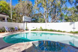 a swimming pool with a sign in front of a house at Riviera Noosa Resort in Noosaville