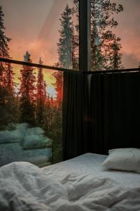 a bed in front of a window with a sunset at Magical Pond Nature Igloos in Ruka