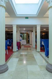 un hall avec colonnes, tables et chaises bleues dans l'établissement Hotel Grand, à Eforie Nord