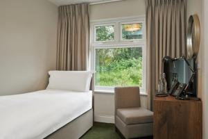 una camera con letto, finestra e sedia di Powerscourt Springs Health Farm a Wicklow