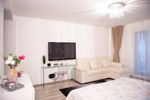a white living room with a white couch and a tv at Kai Mountain Luxury Apartment in Braşov