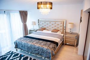 a bedroom with a large bed and a chandelier at Kai Mountain Luxury Apartment in Braşov