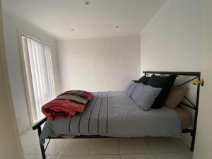 Ce lit se trouve dans un dortoir blanc doté d'une fenêtre. dans l'établissement Port Lincoln Marina Waterfront Apartment, à Port Lincoln