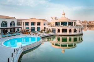 a large building with a pool in the water at Copthorne Lakeview Hotel Dubai, Green Community in Dubai