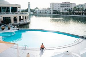 un hombre está sentado en una piscina en Copthorne Lakeview Hotel Dubai, Green Community en Dubái