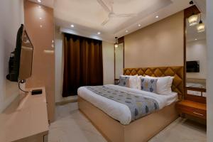 a bedroom with a large bed and a television at Hotel Leo Saffron - Corporate Stay Pitampura in New Delhi