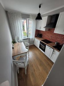 une cuisine avec des placards blancs et une table avec des chaises dans l'établissement Apartament Centrum 1 Maja 35D VIP, à Szklarska Poręba