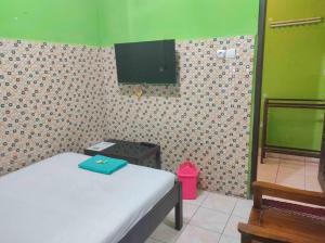 - une chambre avec un lit et une télévision murale dans l'établissement Bayu Murti Inn Kaliurang Yogyakarta RedPartner, à Kaliurang