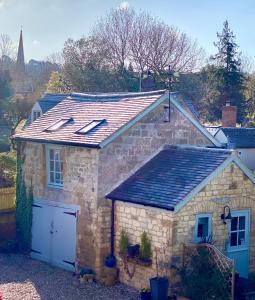 una pequeña casa de piedra con techo y garaje en The Loft in the Malt Barn Chipping Campden en Mickleton