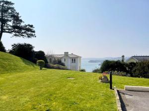a house on top of a grassy hill with the ocean at No2 Ellington Court Apartment in Torquay